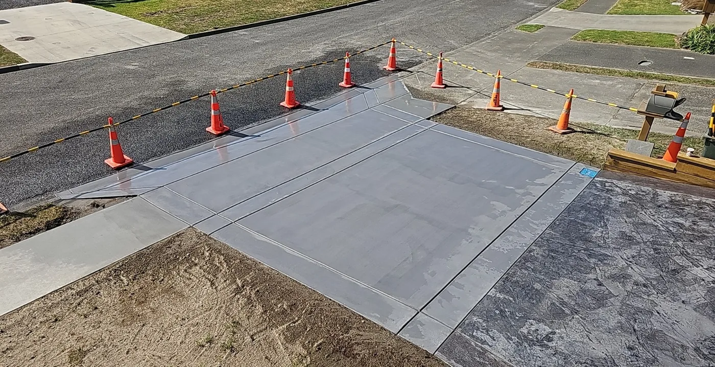 Exposed aggregate driveway leading to a white weatherboard home