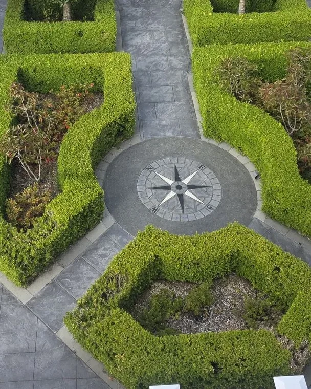 Aerial view of a stamped concrete compass medallion centring a formal topiary courtyard