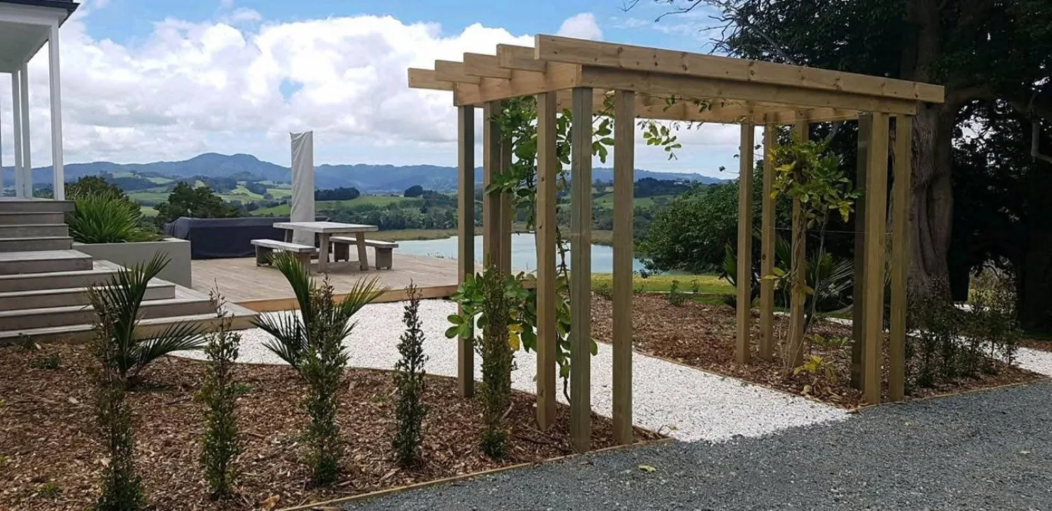 Timber pergola beside a deck overlooking a rural lake and hills