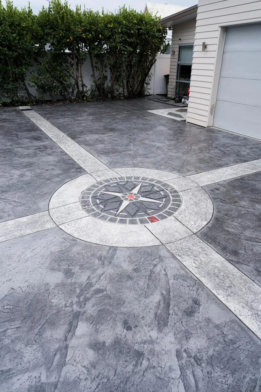 Stamped decorative concrete driveway with a compass rose centrepiece and contrasting banding