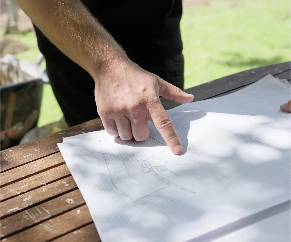 Designer pointing at a hand-drawn site plan for a decorative concrete project
