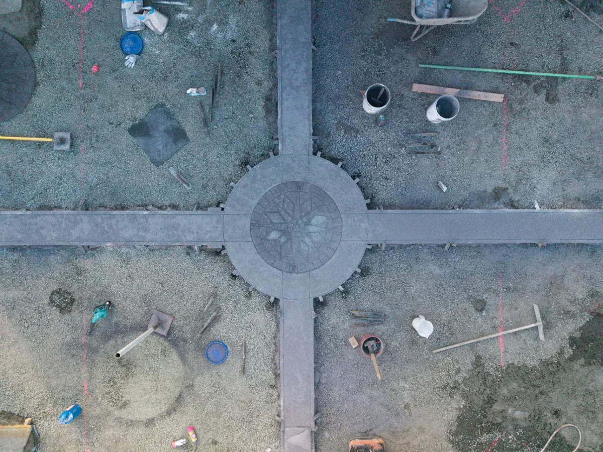 Aerial view of a compass rose medallion being stamped into freshly placed concrete