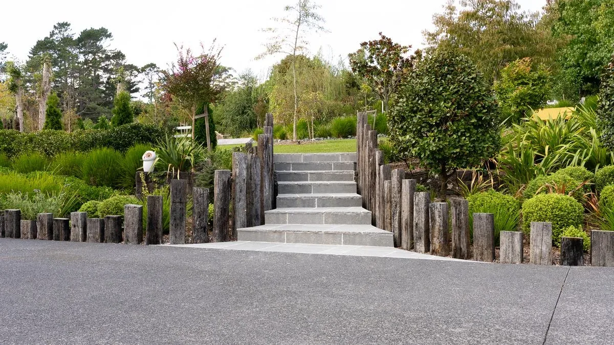 Natural stone staircase with vertical timber sleeper edges and integrated planting on an Auckland landscape