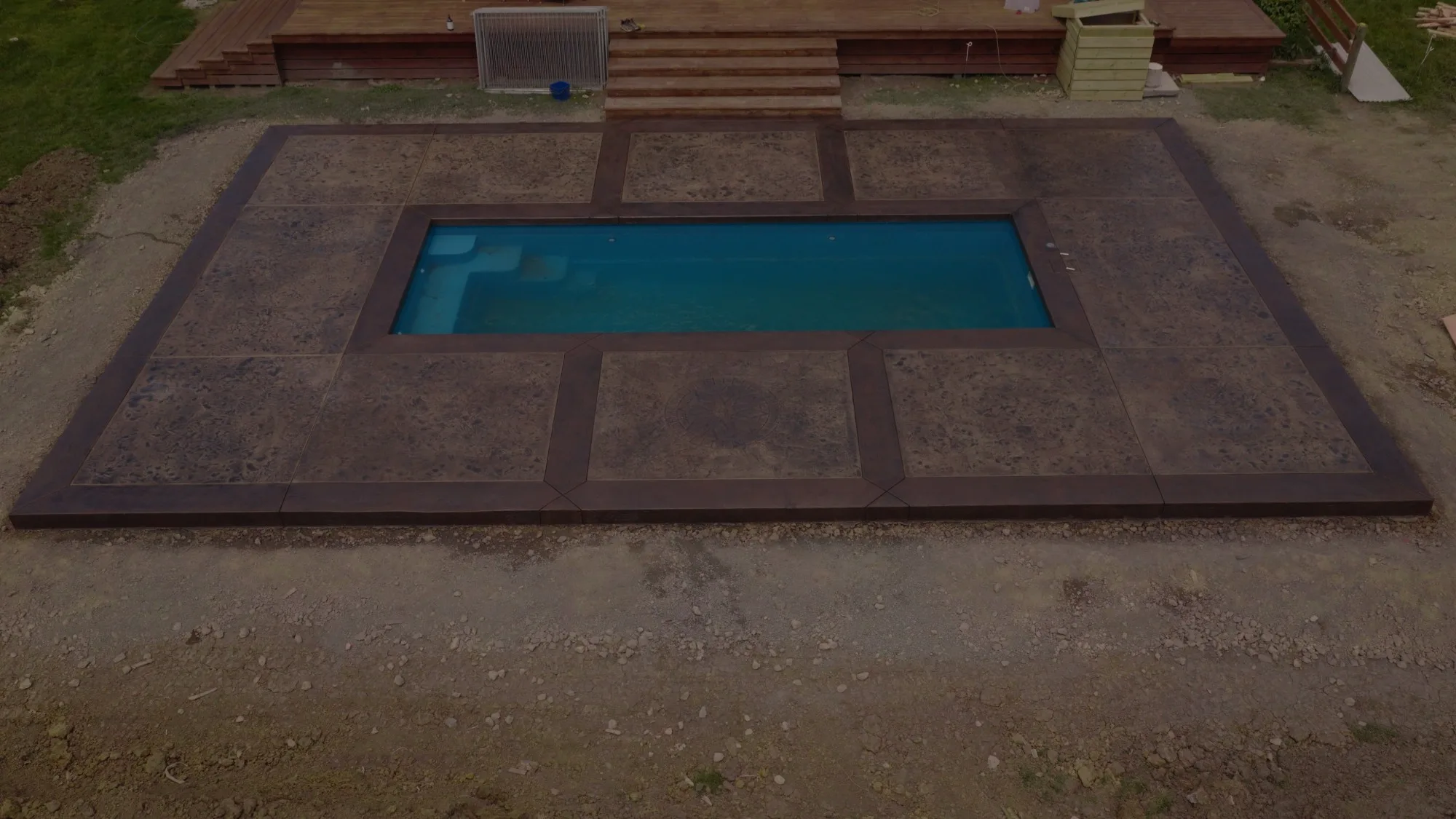 Tangiteroria pool surround: Roman slate panels framed by timber-imprinted concrete borders