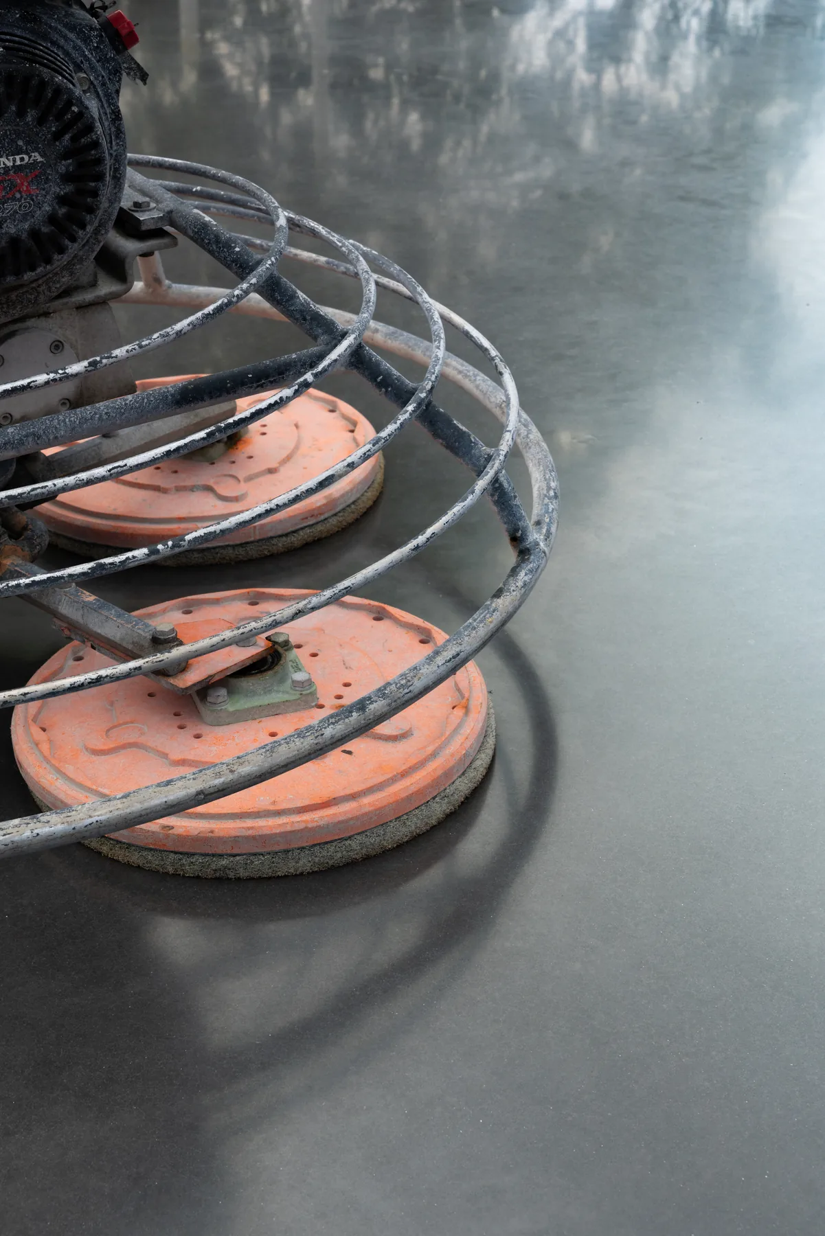 Power trowel pads refining a freshly placed concrete slab to a tight, dense surface